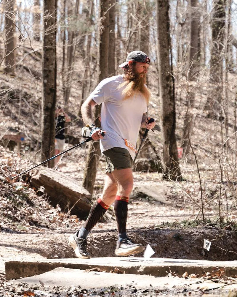 Chadd Wright running a woodland trail with poles.