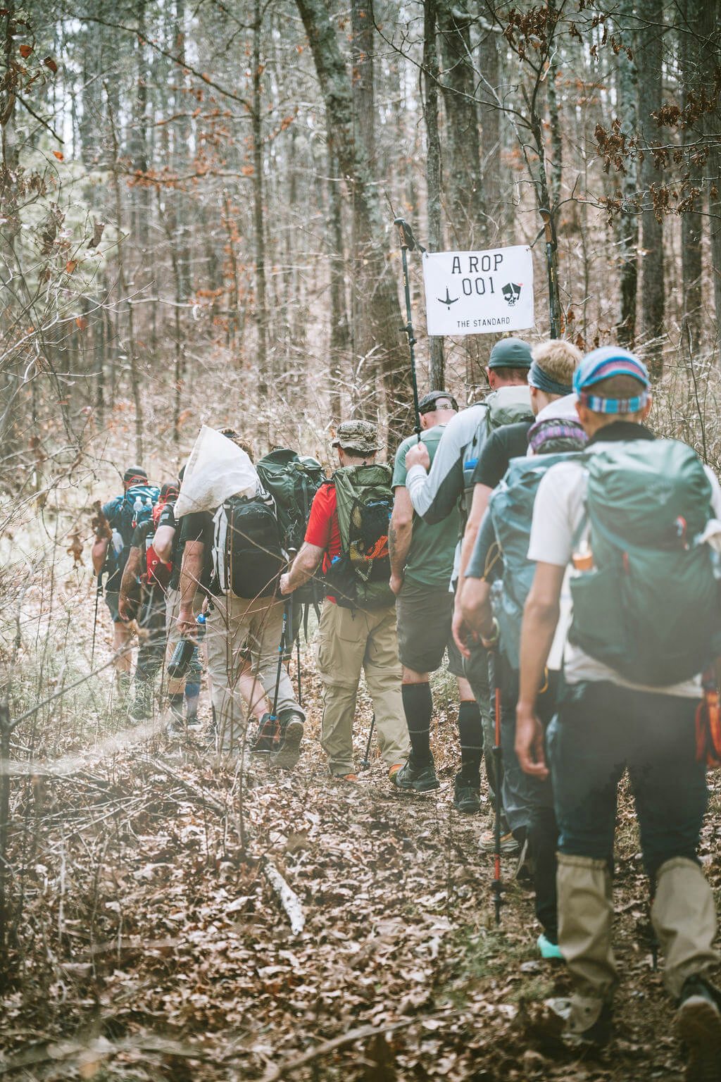 3 of 7 training participants carrying packs along a forest trail